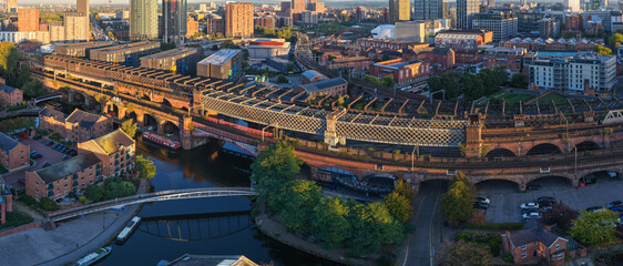 Panoramic sunrise aerial of Castlefield, Manchester, showing railway viaducts, canal boats, and...