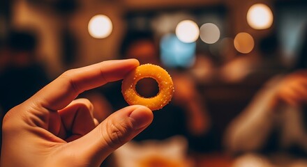 Holding an Onion Ring in a Restaurant Setting.