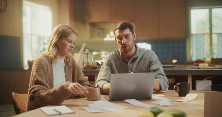 Man and Woman Sitting Behind a Table Together with Laptop Computer, Organizing Monthly Expenses. She Sorts Through Bills and Statements as He Updates the Household Budget Online - Powered by Adobe