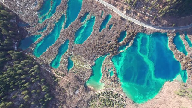 Drone view of Jiuzhaigou National Park in spring in Sichuan Province China. It features cascading waterfalls, turquoise blue lakes, and stunning mountain valleys. 4K fast motion footage travel concept