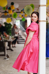 Obraz premium Woman in a pink dress poses gracefully at a vibrant outdoor gathering