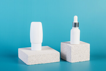 Cosmetic product in tube, bottle, lotion or serum with stylish props on blue background. 