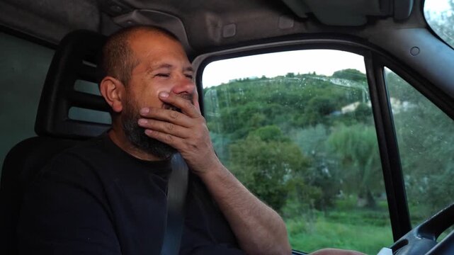 tired truck driver yawning multiple times while driving at sunset, showing exhaustion and the struggle to stay awake on long routes.