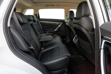  
Luxury car back seat with black leather, fold-down armrest and cup holders