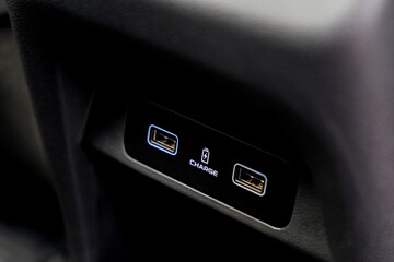 Close-up of dual USB charging ports in car interior panel, labeled with battery icon and CHARGE text