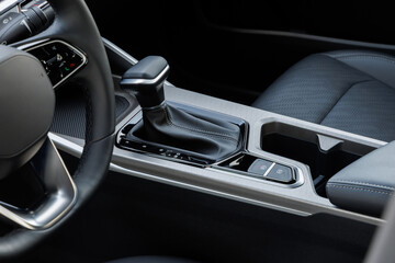 Modern car center console with black leather gear shifter, drive mode button and perforated passenger seat