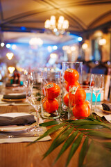 Bright orange fruits in clear vases decorate a festive dining table setting