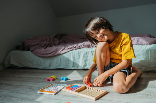 Child playing educational logic board game on bedroom floor