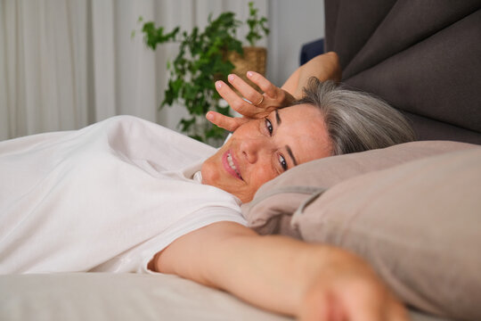 Smiling adult waking up in bed during morning routine at home