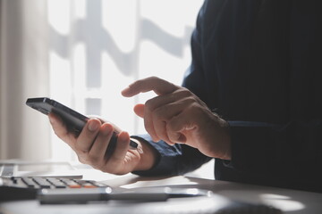 Side view shot of a man's hands using smart phone in interior, rear view of business man hands busy using cell phone at office desk, young male student typing on phone sitting at wooden table, flare