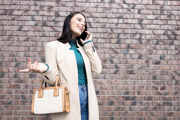 A joyous woman laughs while chatting on her phone, perfectly styled, revealing a sense of warmth in an urban setting.