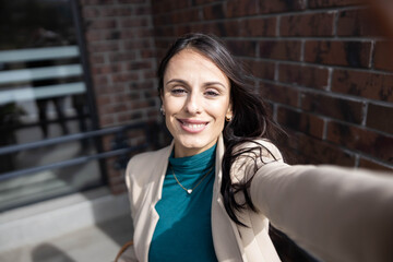 A joyful woman captures her fun spirit while taking a selfie on a sunny day, radiating confidence and delight.