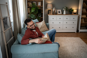 Obraz premium Young man relaxing on sofa enjoying a good book