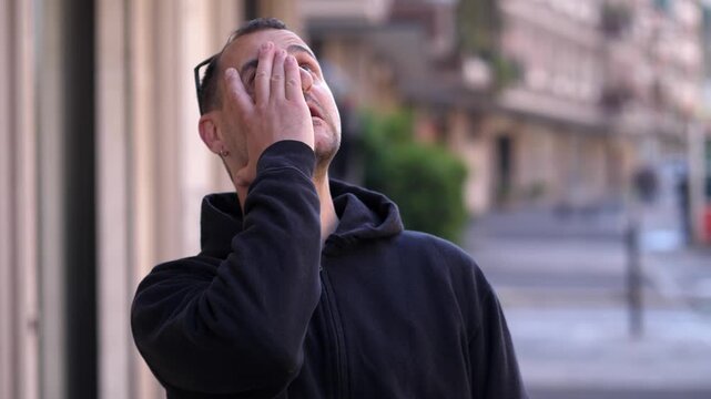 A man covers his face realizing he forgot something, expressing embarrassment, distraction, and human imperfection in a spontaneous urban moment