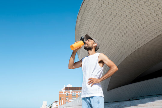 Runner drinking water outside MAAT Lisbon after morning exercise