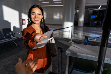Businesswoman handing boarding pass at airport check-in counter