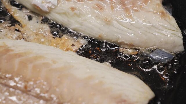 Preparing fresh fish fillet in a hot pan with oil to make a delicious meal, close-up of white fish fillet. High quality 4k footage