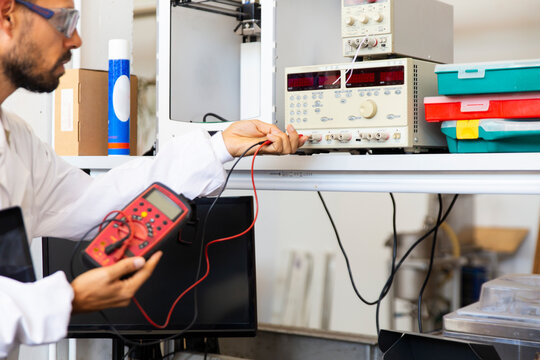 Lab technician testing electronics with voltage meter in innovation lab