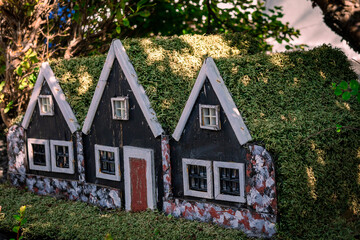Garden decoration three small black wooden elf houses with green moss roof, typical for Iceland. 