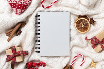 Gray blank spiral notebook on white knitted sweater near Christmas decor, winter Holiday mockup