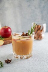 Hot apple cider with cinnamon, anise, and rosemary in glass on a light background