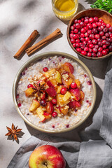 Overnight oatmeal with apples, cranberries, and cinnamon in a bowl on a light background