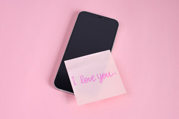 Handwritten I Love You Note On Pastel Pink Sticky Paper Resting On Smartphone