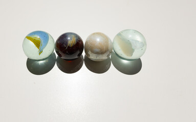 Marbles of various colors on a white background, with their shadows.