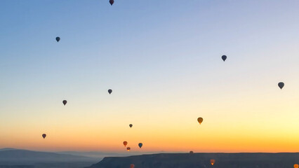 Silhouettes of hot air balloons drifting across a gradient sky during sunrise over the Cappadocia valley, a tranquil scene