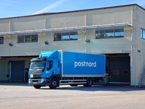 Postnord delivery truck parked near a warehouse, logistics and shipping concept