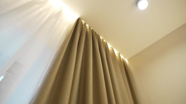 Stylish curtains hang from hidden cornice with soft lighting creating cozy elegant mood. Room achieves modern cozy balance with elegance