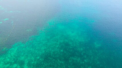 Aerial view of clear turquoise ocean water revealing coral reefs and distant small tropical islands under a blue sky, Siargao, Philippines. - Powered by Adobe