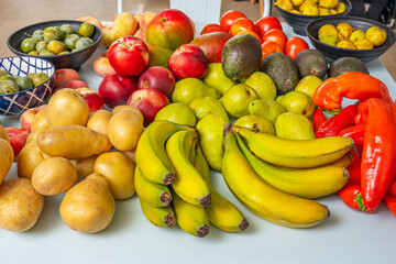 Fresh market composition with  bananas, blanquilla pears, avocados,  potatoes, nectarines, and figs on a soft sky blue tabl