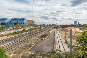 Parallel commuter rail tracks entering a lit tunnel, with reflective side markings and a drainage system next to the rails.