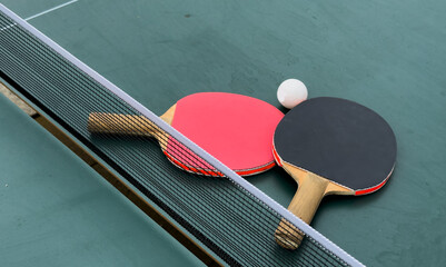 Two ping pong rackets and ball on table