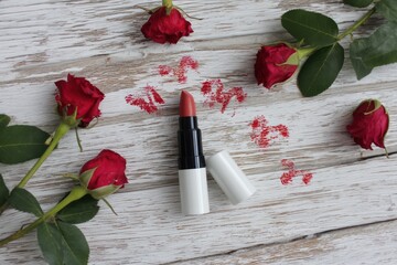 White wooden background with roses, lipstick, and kisses for 8 March