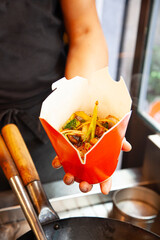 Fast food restaurant, udon in a takeout package. Chef preparing