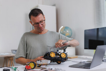 Man assembling robotic car hobby project with tool