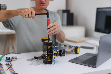 Person assembling robot car using tools on desk