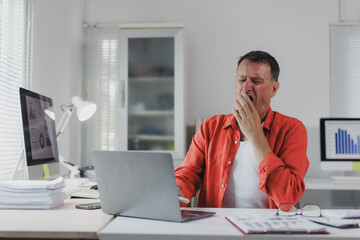 Tired man yawning working from home office