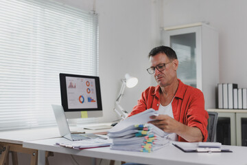 Mature man analyzing financial documents at home office