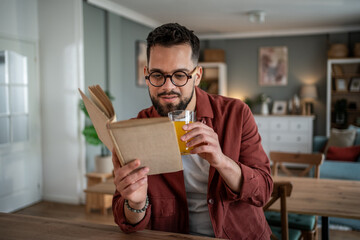 Young man relaxing reading book enjoying orange juice