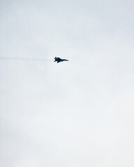 UAF Mig-29 flying in cloudy sky. Dark silhouette - side view of air superiority fighter plane.