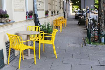 KRAKOW, POLAND - JUNE 24, 2025: A street cafe with yellow chairs set on the sidewalk.