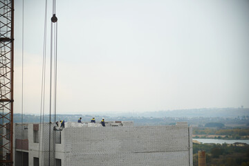 workers are laying bricks on the top floor of the construction site