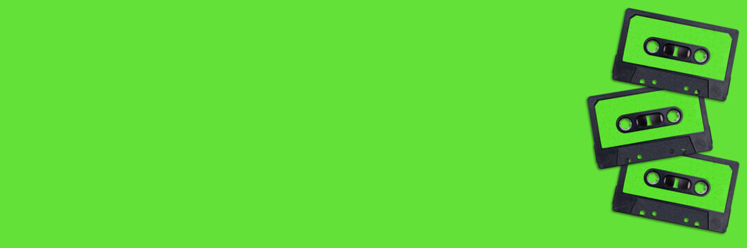 Top view of vintage audio cassette tapes flat lay on colorful green background. Creative 80s Banner. Retro minimal Pop Art design. music concept.