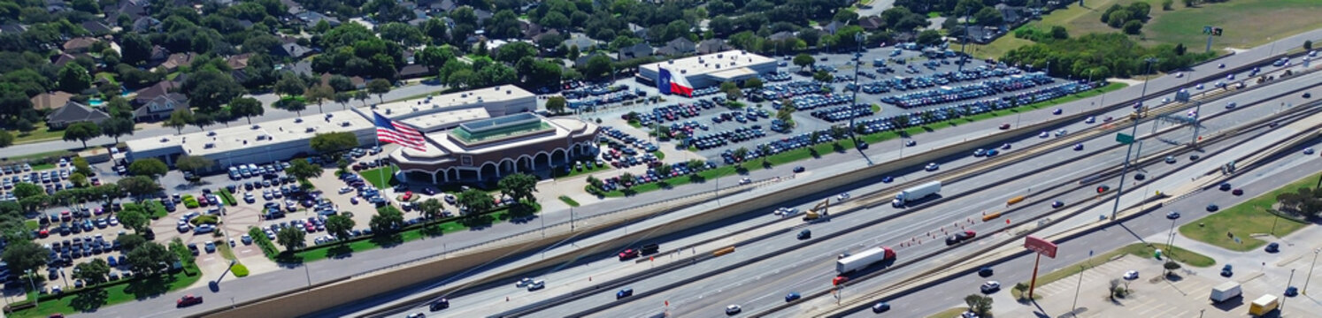 Fototapeta Panorama aerial view commercial zone North Richland Hills, Texas with multilane highway bridge-over-underpass, dealership packed parking dual American, Texas flags, lakeside green suburban area
