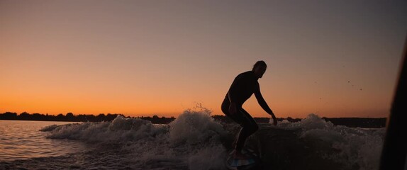 A skilled surfer gracefully rides a wave at sunset, showcasing agility and balance against a vibrant sky, capturing the essence of adventure and water sports. - Powered by Adobe