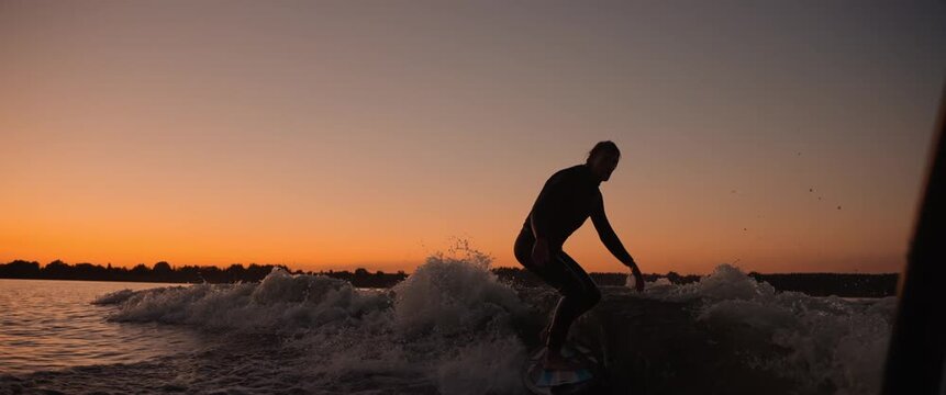 A skilled surfer gracefully rides a wave at sunset, showcasing agility and balance against a vibrant sky, capturing the essence of adventure and water sports.