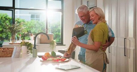 Senior couple, flowers and hug in kitchen with care, present or anniversary with love in home. Elderly man, woman and embrace with floral bouquet, happy or gift with cooking in retirement at house - Powered by Adobe